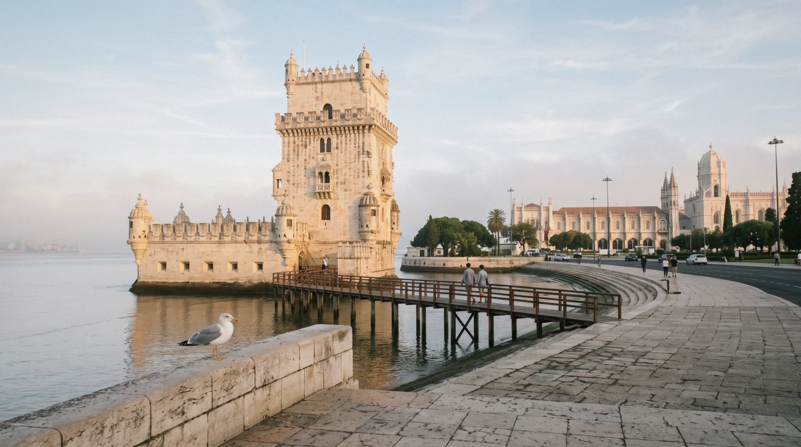 The Manueline keep of the tower at Belém seen across the water at first light with the long monastery facade behind, the two choices in the Belém Tower vs Jerónimos decision, Lisbon