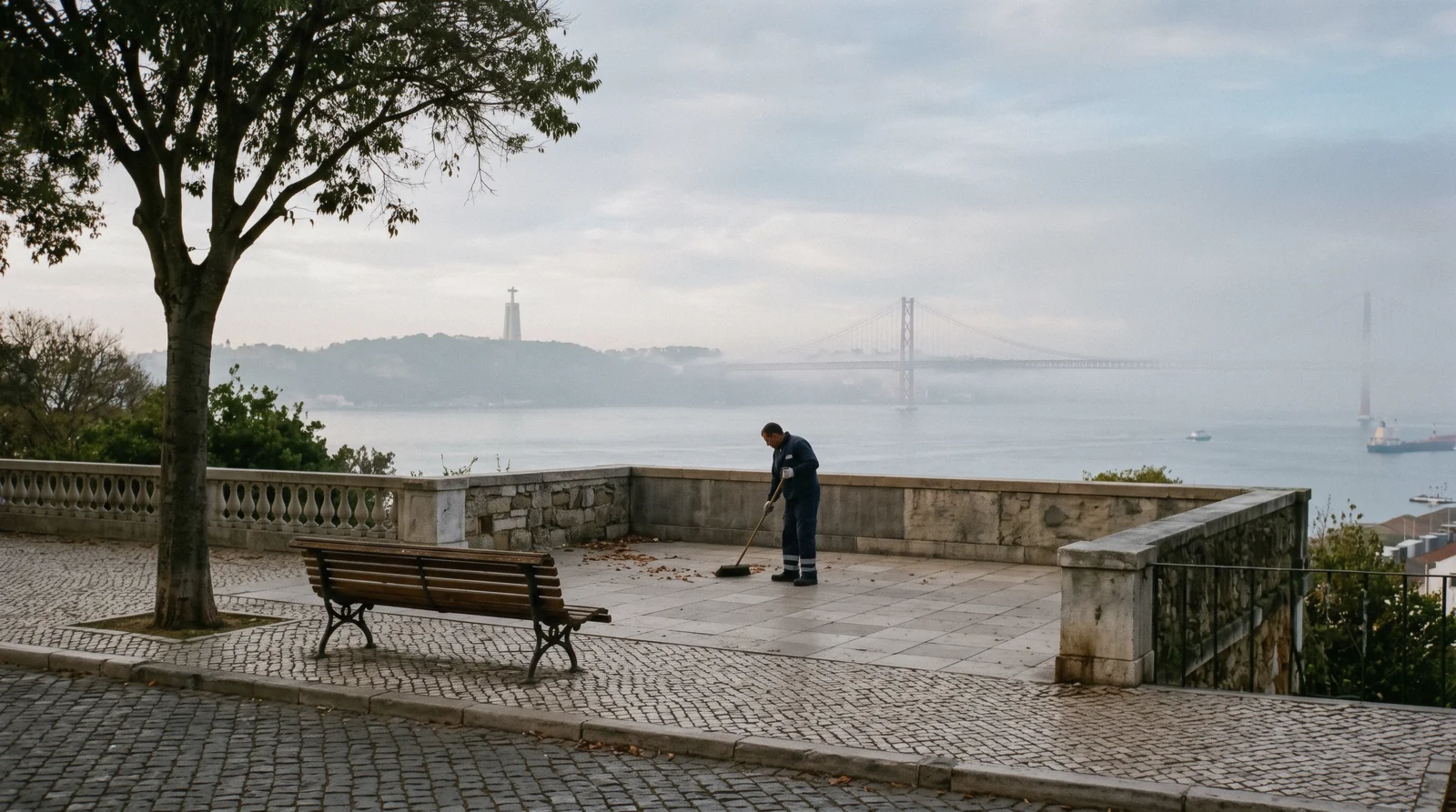 Morning mist lifting off the Tagus below the Miradouro da Graça at 07:50, the bridge and Cristo Rei faint beyond, the starting view for a Lisbon trip planner