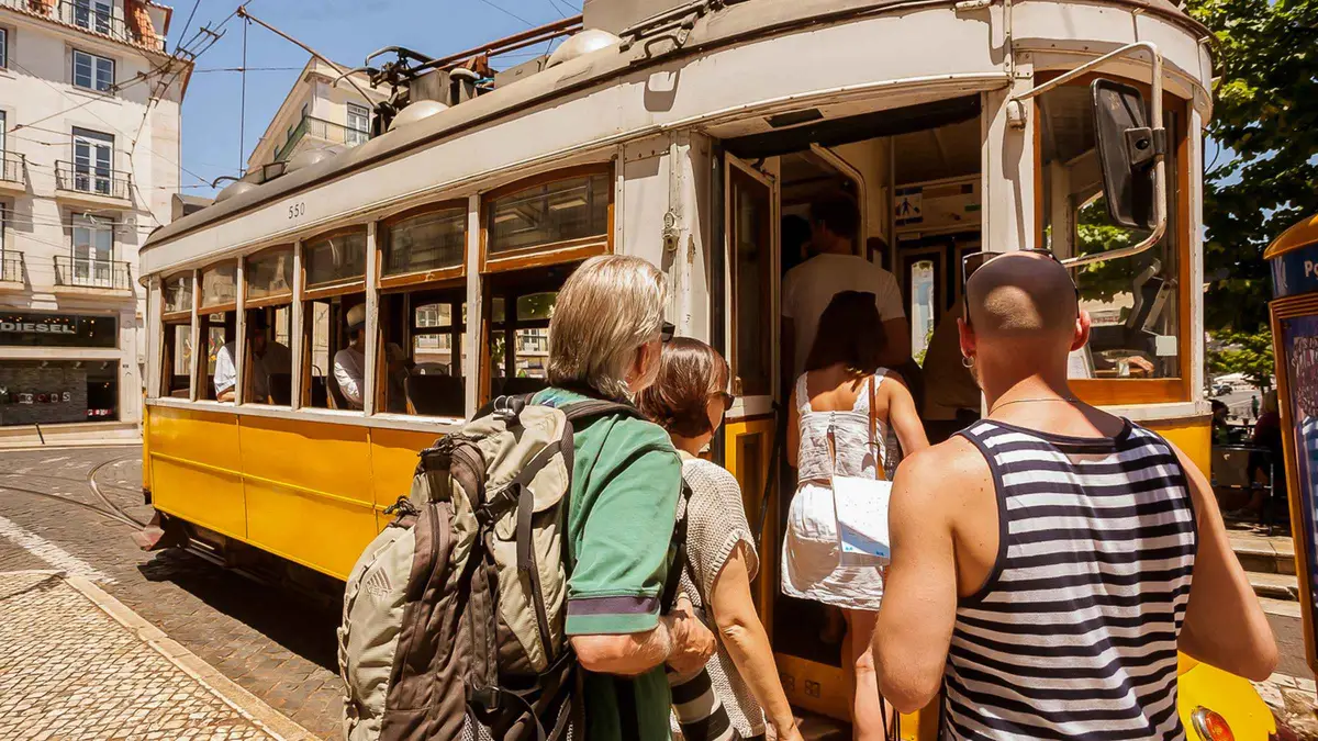 A yellow Carris tram 28 climbing a narrow cobbled street in Graça, the historic tram on a Lisbon, Portugal must-see list