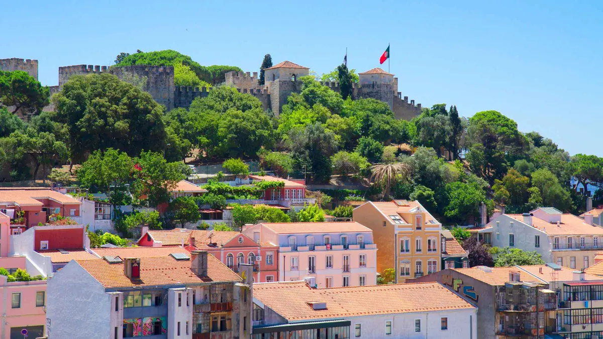 The stone ramparts of São Jorge Castle above the red roofs of Alfama, the oldest district on a Lisbon, Portugal must-see walk