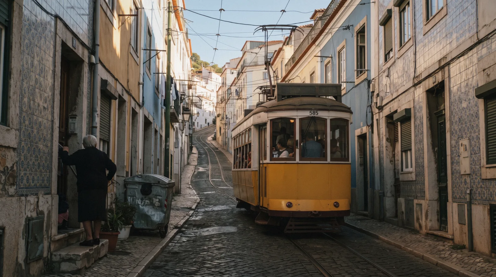 A yellow Remodelado tram 28 squeezing through the narrow Rua das Escolas Gerais in Alfama at 08:10, tram 28 Lisbon
