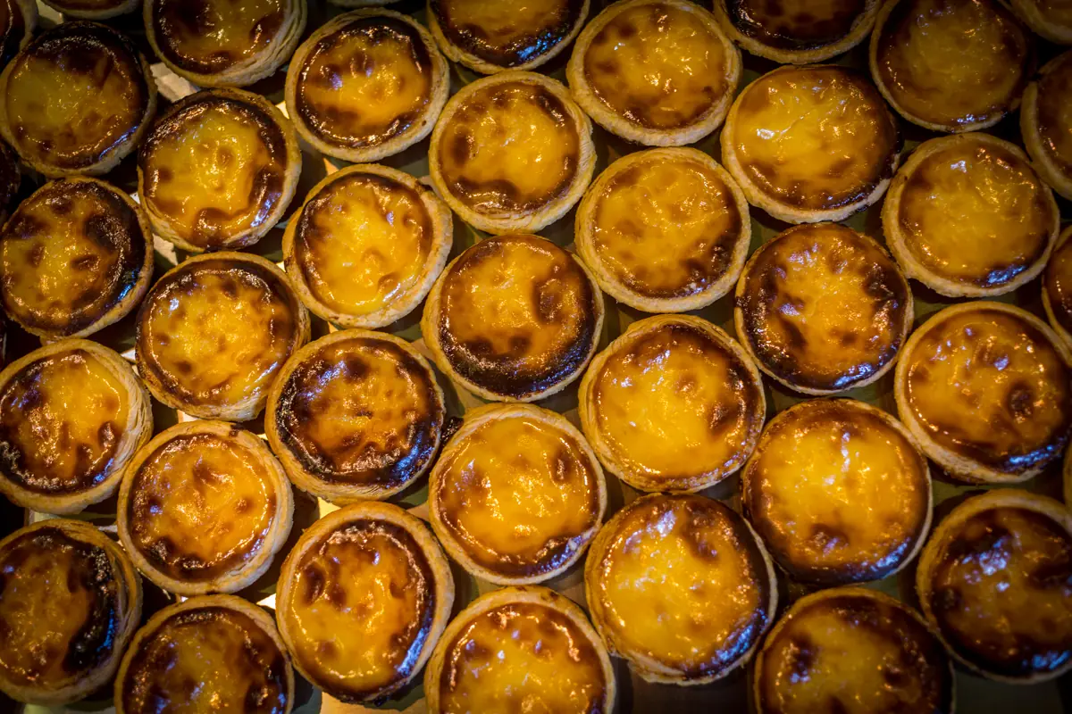 Trays of freshly baked pastéis de nata, the custard tops blistered dark from the oven